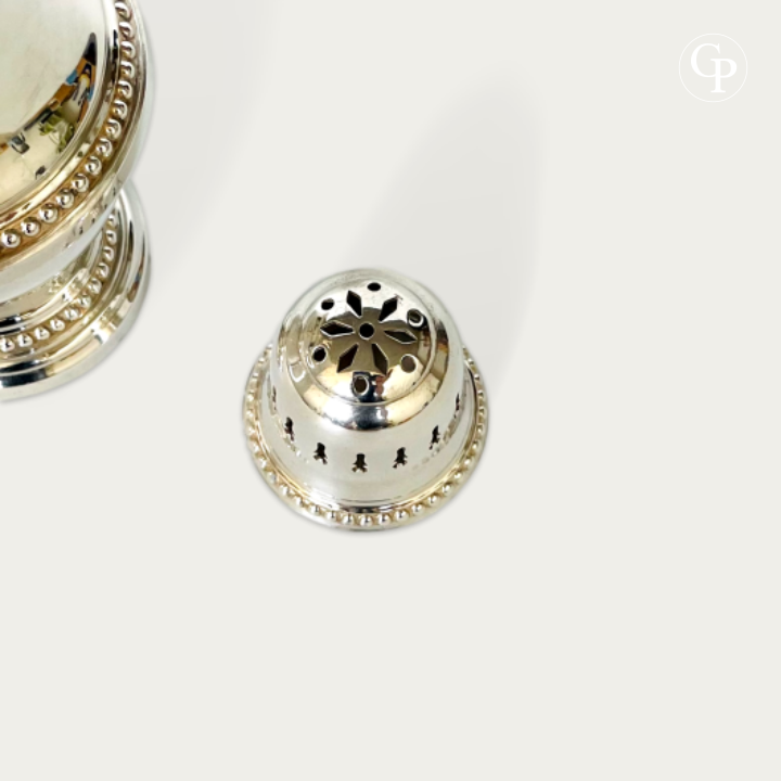 Top view of the finely pierced floral and geometric patterns on silver sugar shaker | Vue de dessus du travail d'ajourage géométrique et floral du dôme en métal argenté
