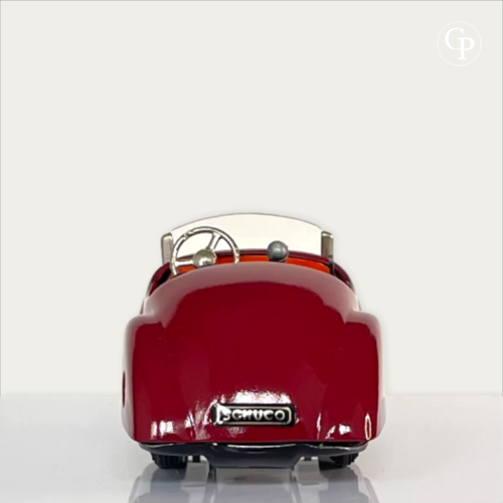 Strict rear view of the deep red Schuco Examico 4001 vintage tinplate roadster, showcasing the Schuco license plate, cockpit interior, and chrome steering wheel on a light background. | Vue de dos de la voiture automate Schuco Examico 4001 de couleur bordeaux, mettant en valeur la plaque d'immatriculation Schuco, l'intérieur de l'habitacle et le volant chromé sur fond clair.