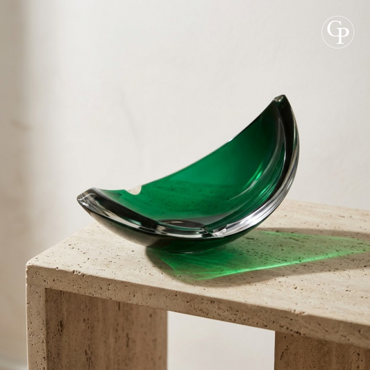 Vide-poche demi-lune en cristal vert René Delvenne posé sur une console en travertin beige | Mid-century green crystal crescent bowl by René Delvenne displayed on a beige travertine console table